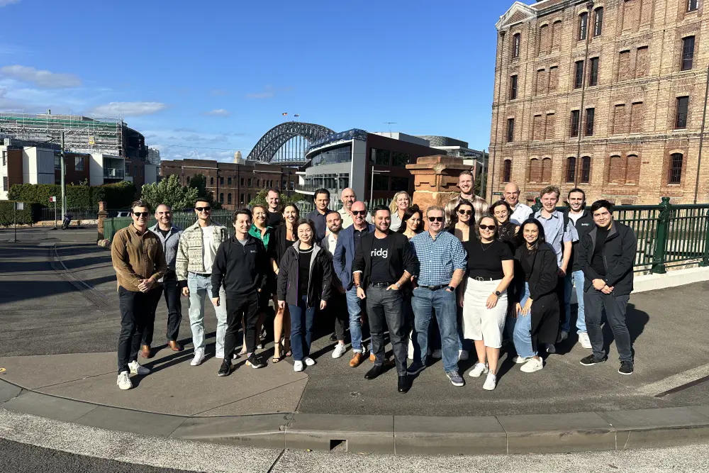 The Bridgit team outside a brick building with the Sydney Harbour Bridge behind them