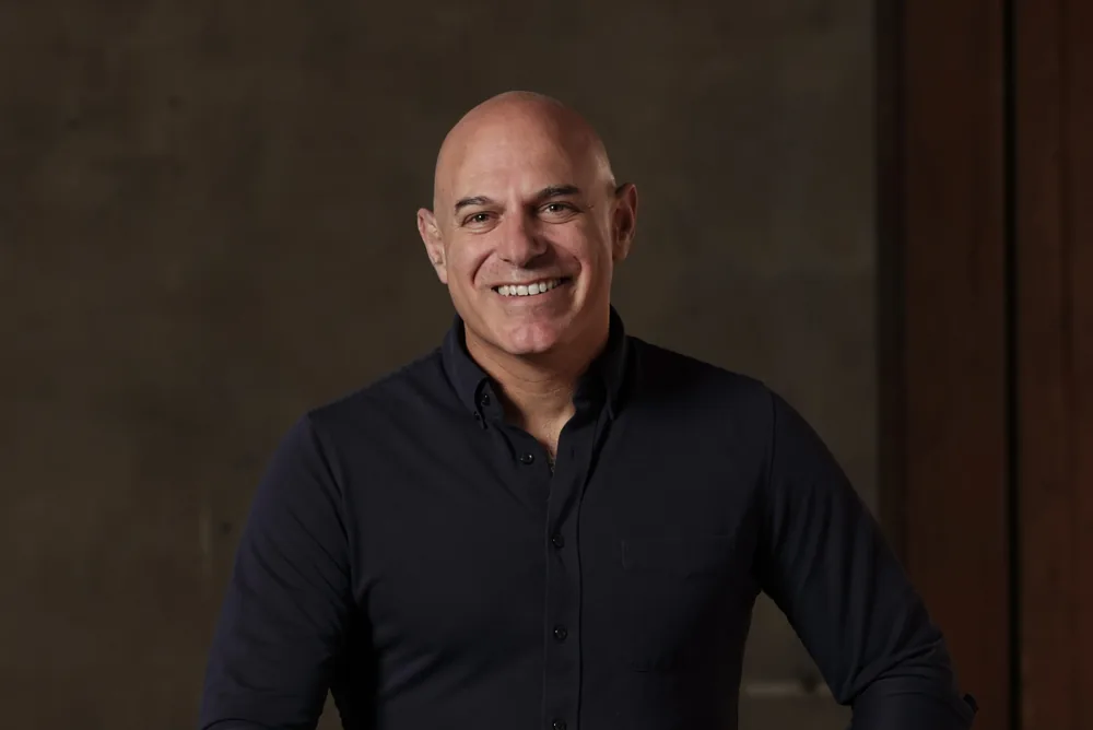 Jon Abitz, CTO at Bridgit, smiling as he sits on a stool in a dark shirt.