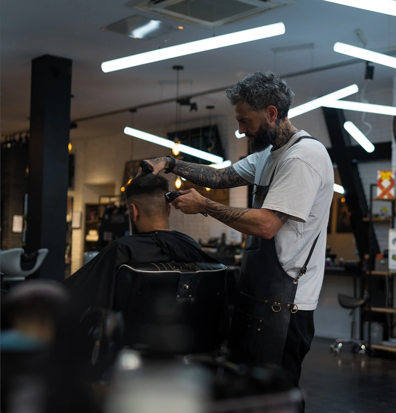 Barbier aux cheveux gris taillant les cheveux d un client à la tondeuse INDUSTRIE Barbers