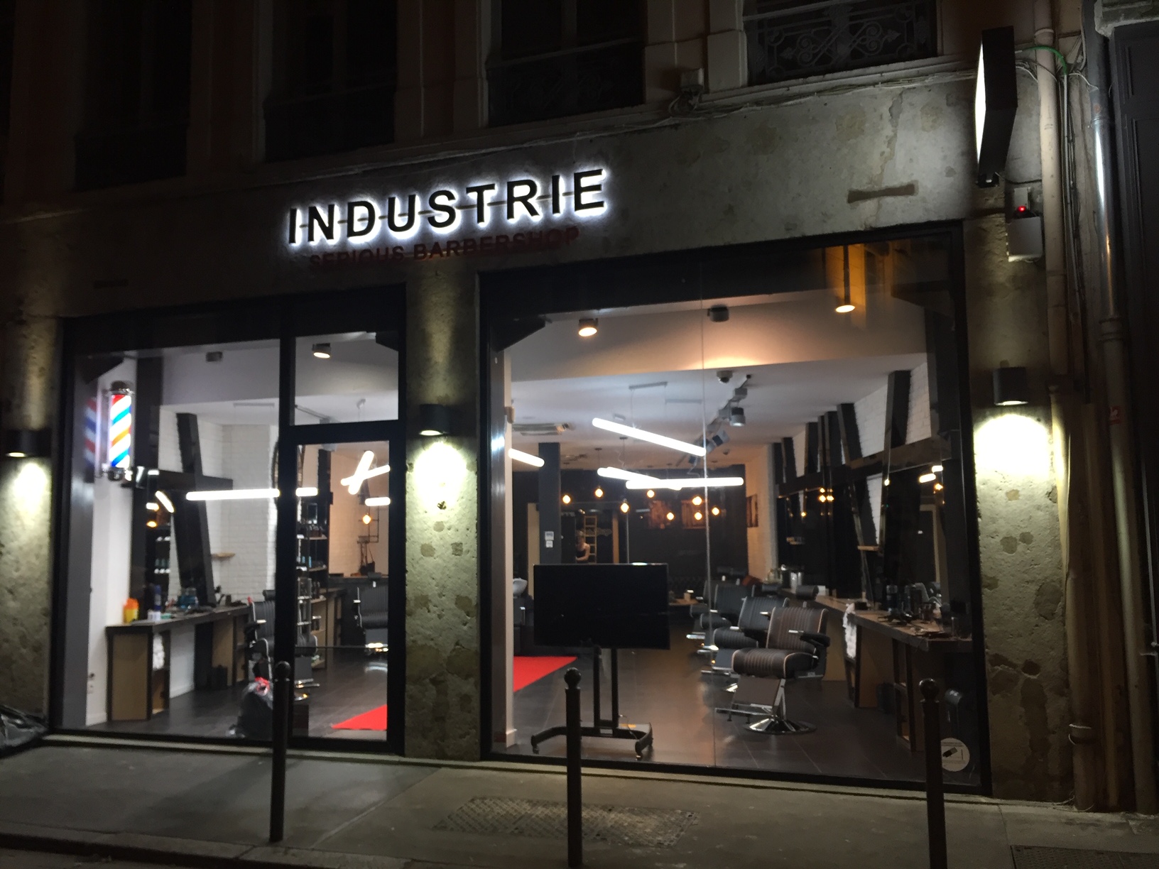 Façade extérieure INDUSTRIE Barbers Lyon de nuit avec enseigne lumineuse