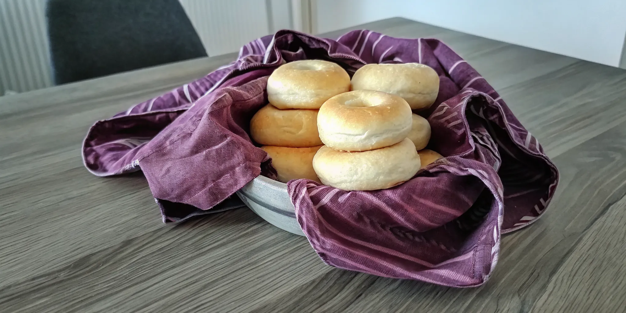 A stack of fresh golden Gryfe's Bagels on a rustic wooden table with cream cheese