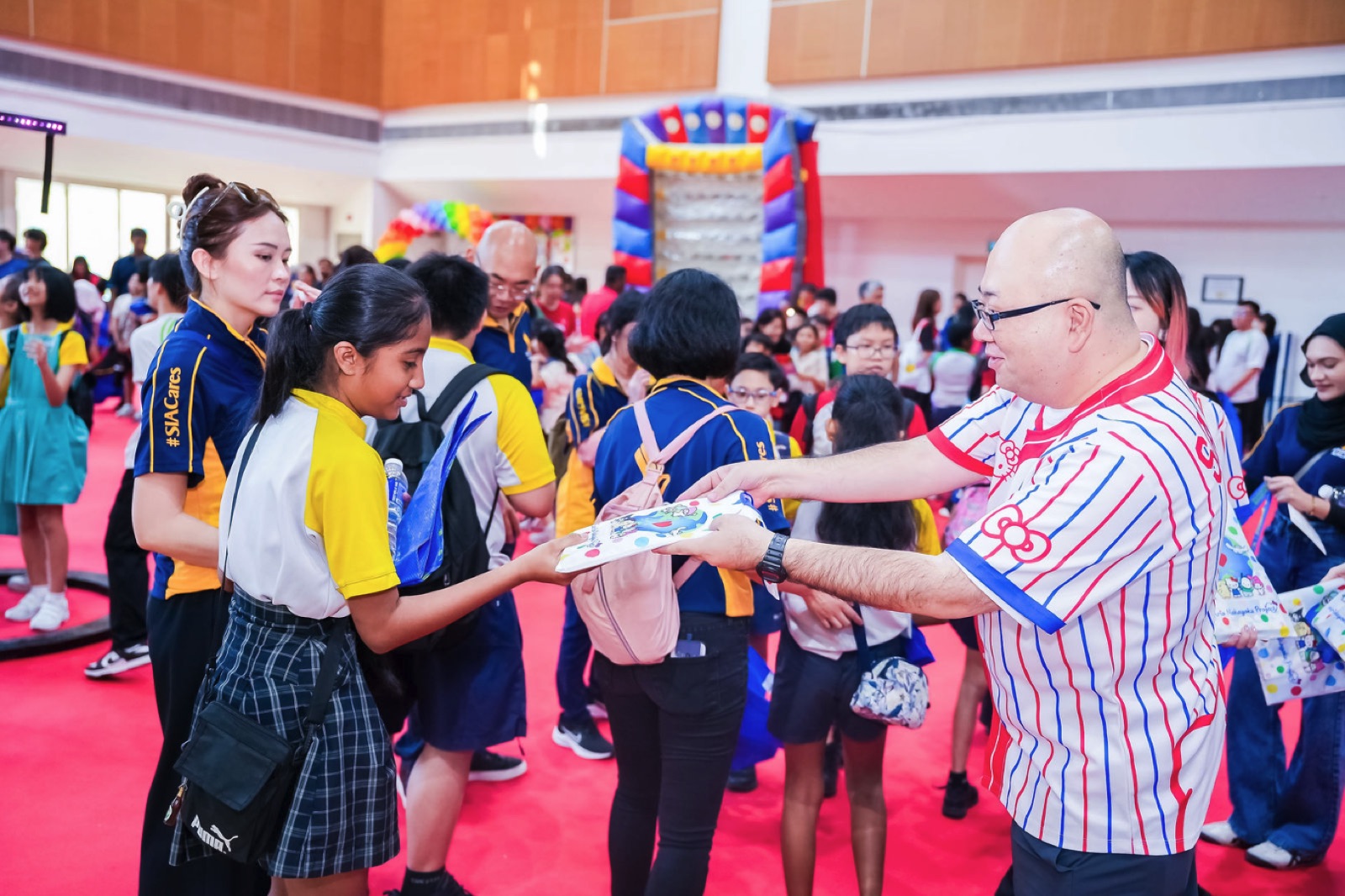 A volunteer handing a gift to a student at Toy Buffet 2025