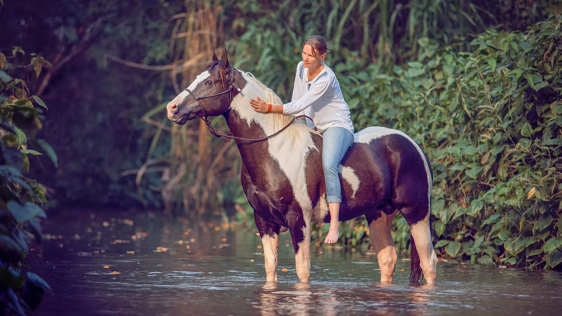 Mujer montando a caballo por un río en Hacienda La Danesa.