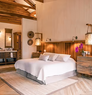 Luxurious bedroom suite with a king-size bed and exposed wooden beams at Hacienda La Danesa.