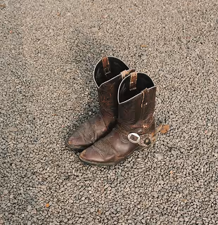 Brown leather cowboy boots on gravel.