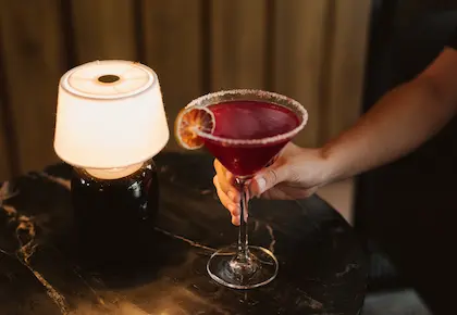 Red cocktail garnished with an orange slice served at the Hacienda La Danesa bar.