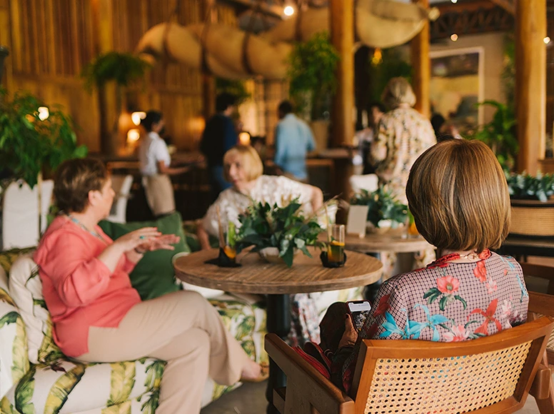Guests chatting over drinks at a round table in the tropical lounge bar of Hacienda La Danesa