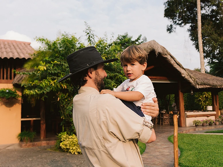Father holding his young son in the gardens in front of Hacienda La Danesa farmhouse