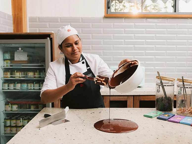 Pastry chef pouring tempered chocolate onto a marble surface at Hacienda La Danesa chocolate workshop