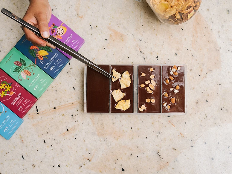 Handcrafted La Danesa chocolate bars with dried pineapple and almonds, next to branded packaging