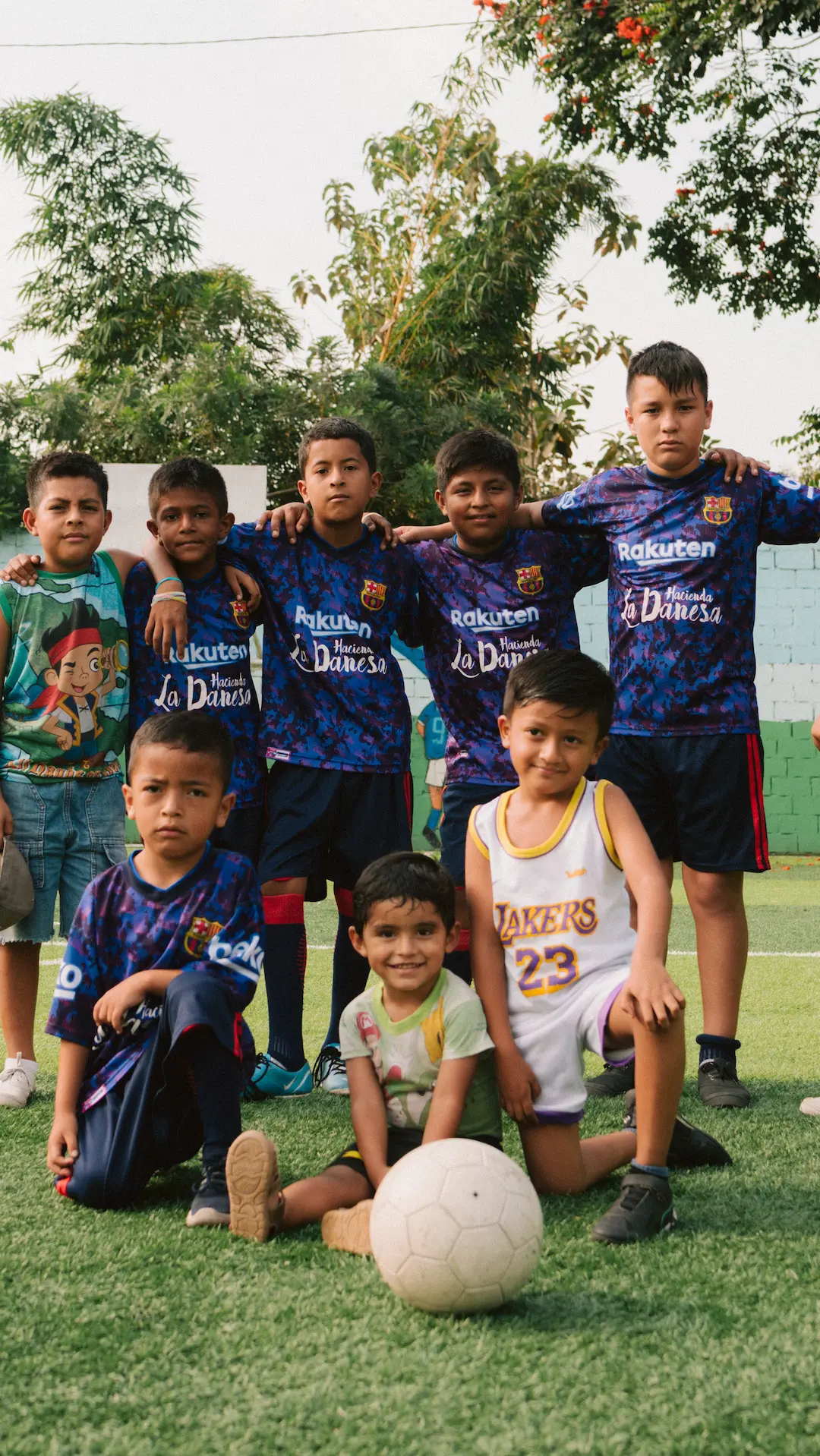 Local children wearing Hacienda La Danesa sponsored jerseys posing on a football pitch in Naranjito, Ecuador