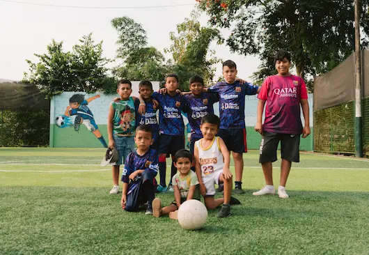 Youth football team sponsored by Hacienda La Danesa posing together on a community pitch in Naranjito
