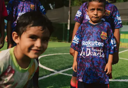 Two young boys wearing Hacienda La Danesa sponsored football jerseys on a local pitch in Naranjito