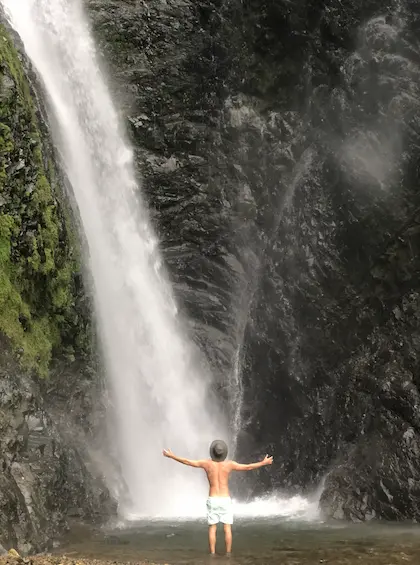 Huésped con brazos abiertos frente a una gran cascada en una excursión desde Hacienda La Danesa, Ecuador