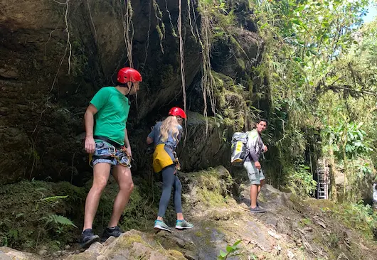Huéspedes con cascos y arneses explorando un cañón en la selva en una excursión guiada desde Hacienda La Danesa
