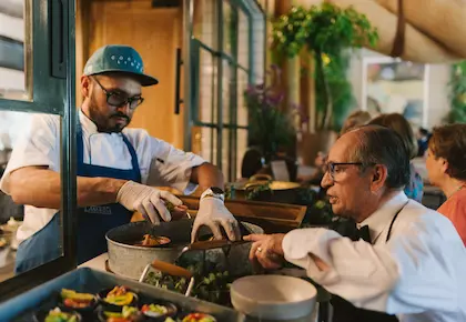 Chef plating dishes at the pass with a waiter at Helge Restaurant, Hacienda La Danesa