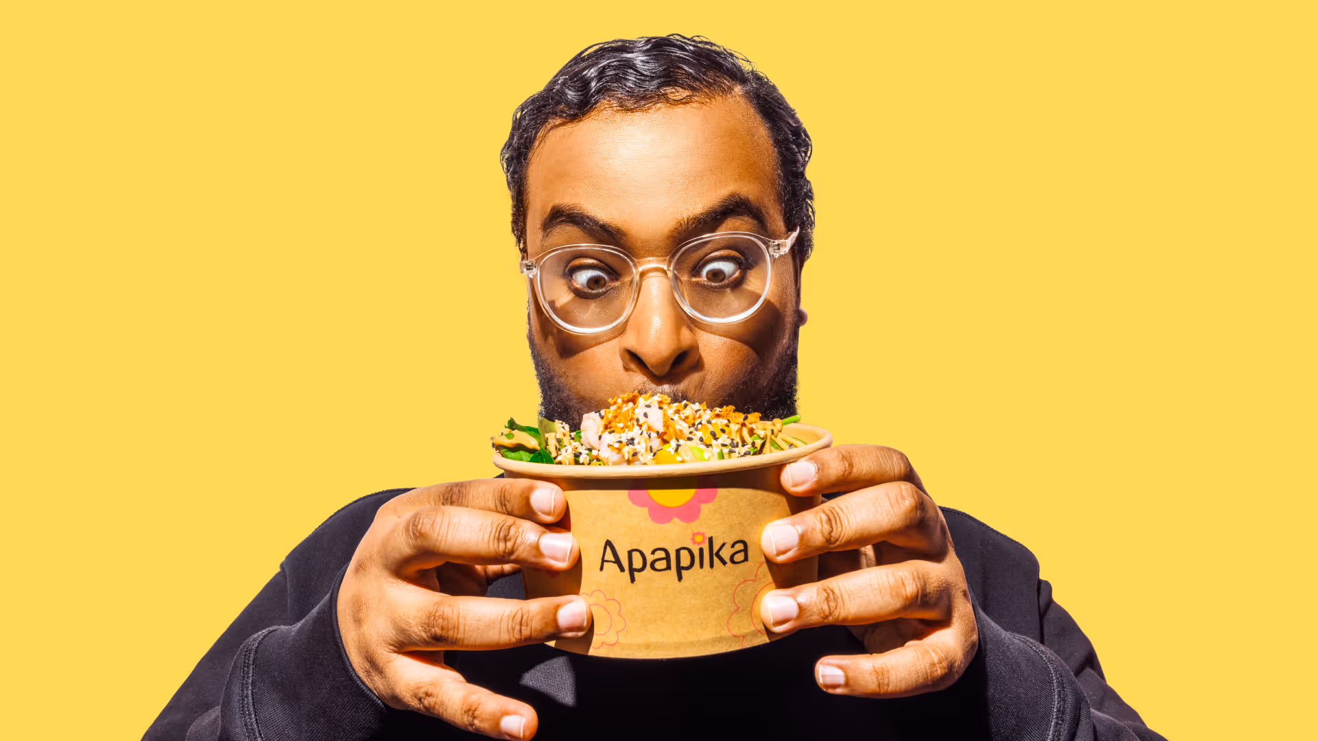 Ein Mann mit Brille hält eine Schüssel mit einem bunten Salat und schaut begeistert darauf.