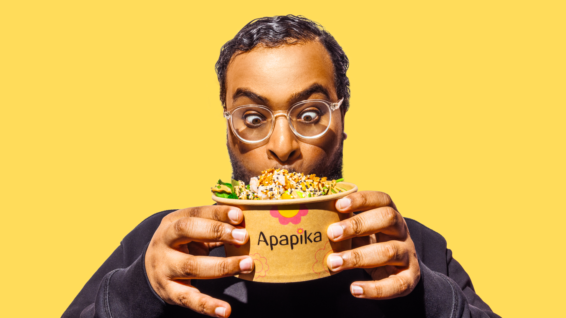 Ein Mann mit Brille hält eine Schüssel mit einem bunten Salat und schaut begeistert darauf.