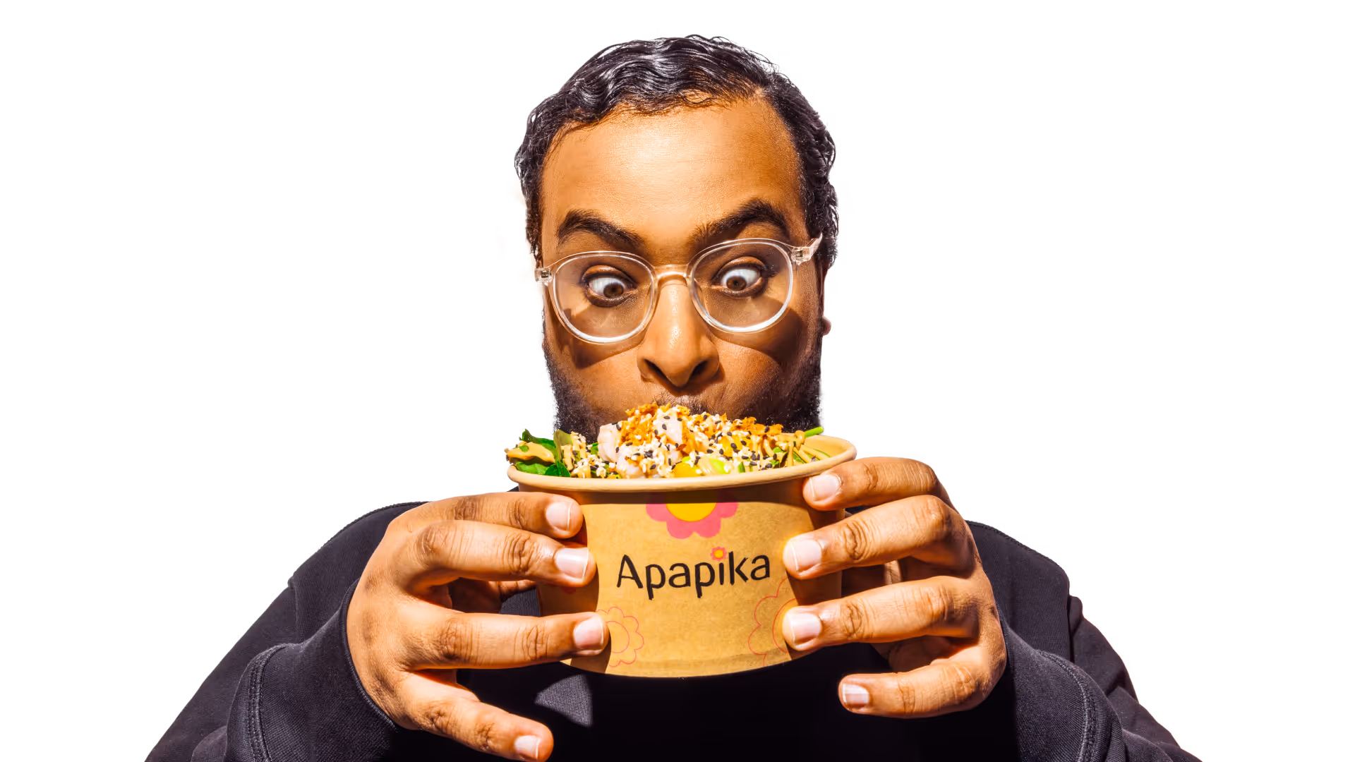 Ein Mann mit Brille hält einen Becher mit Salat von Apapika und schaut überrascht darauf.