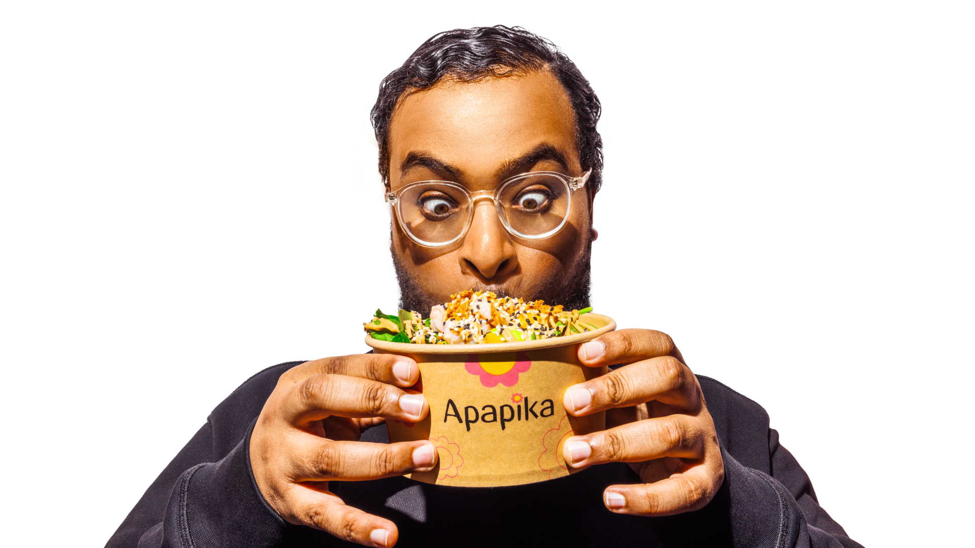 Ein Mann mit Brille hält einen Becher mit Salat von Apapika und schaut überrascht darauf.