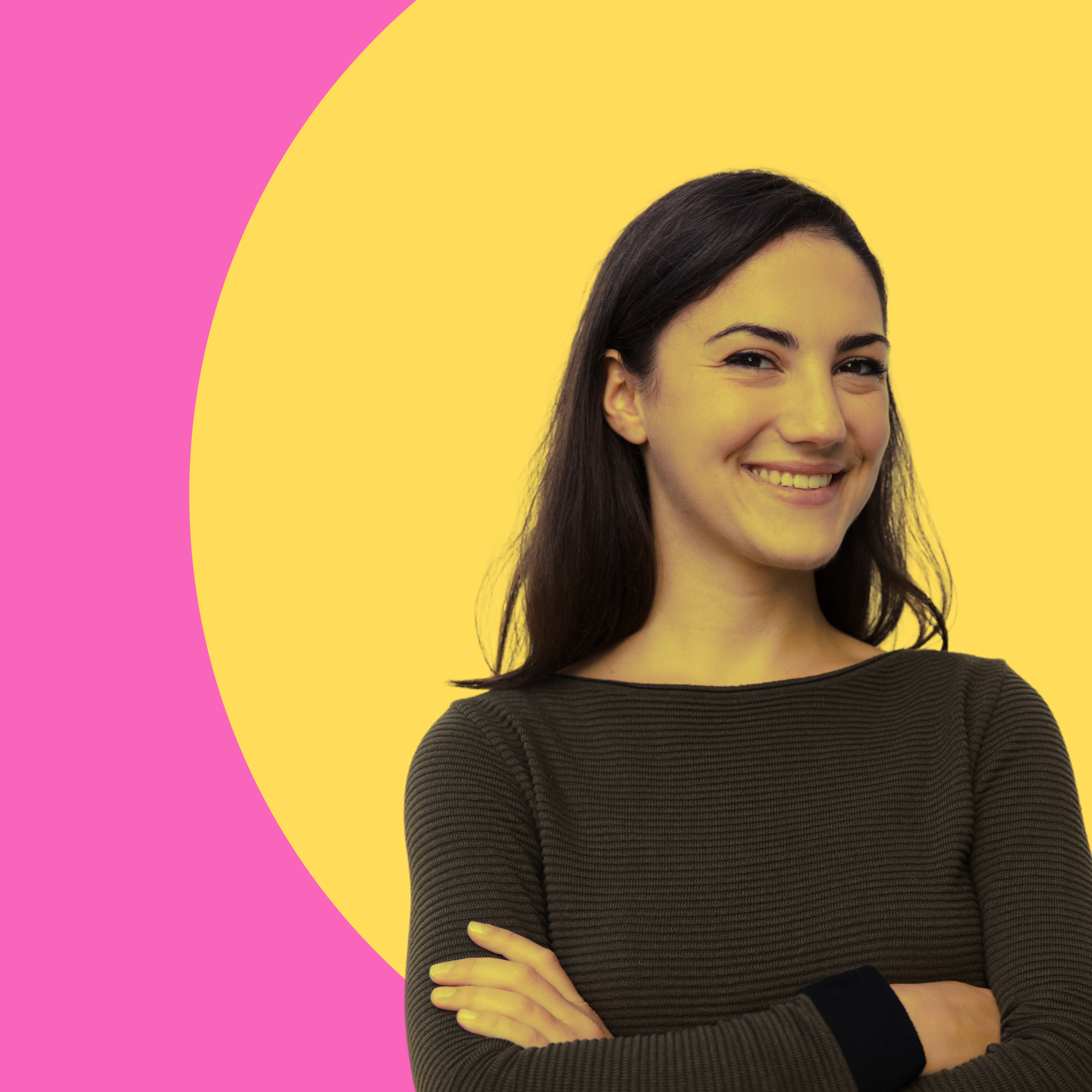 Junge Frau mit langen dunklen Haaren lächelt mit verschränkten Armen vor einem gelben und pinken Hintergrund.