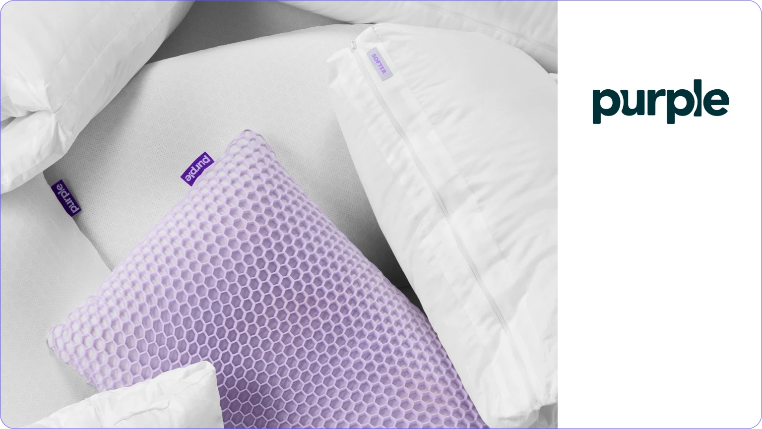 Purple brand bedding with a purple hexagonal grid cushion and white pillows on a mattress.