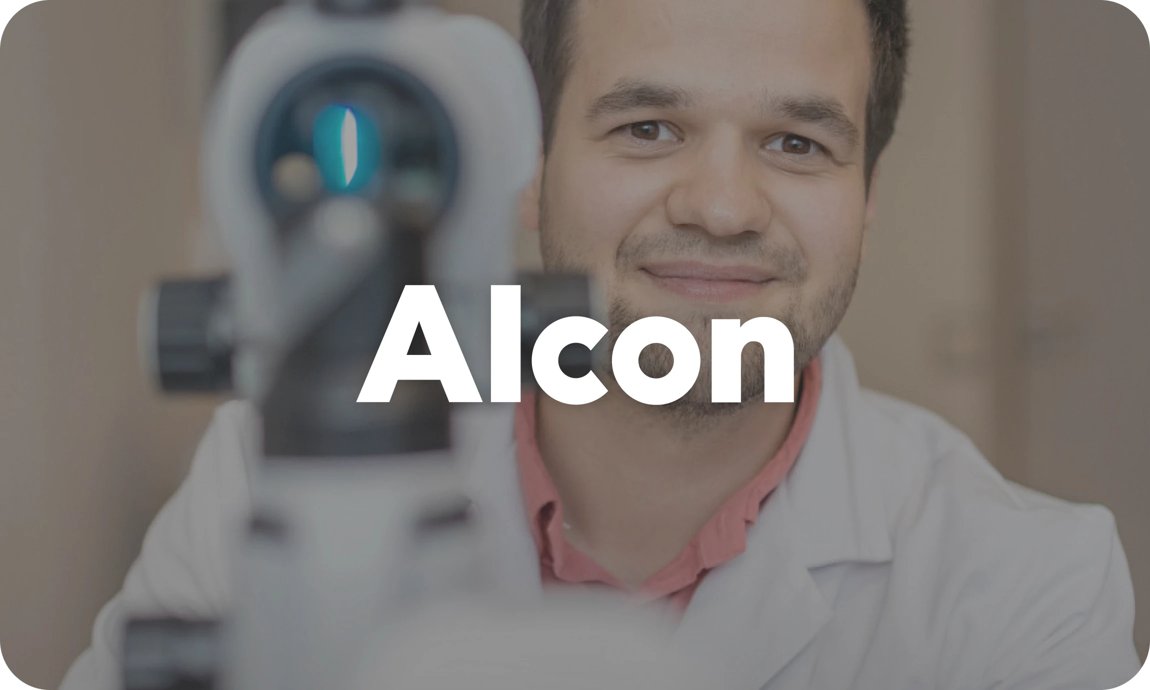 Smiling man in a lab coat behind a microscope with the word Alcon overlayed.