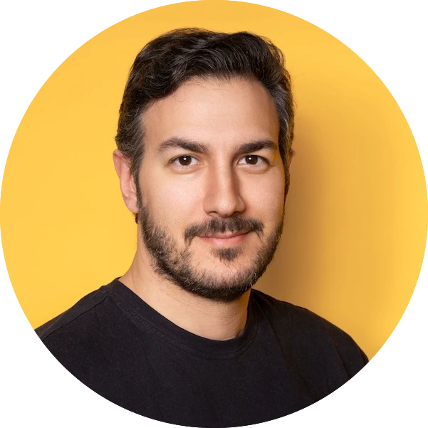 Portrait of a man with dark hair and beard wearing a black shirt against a yellow background.