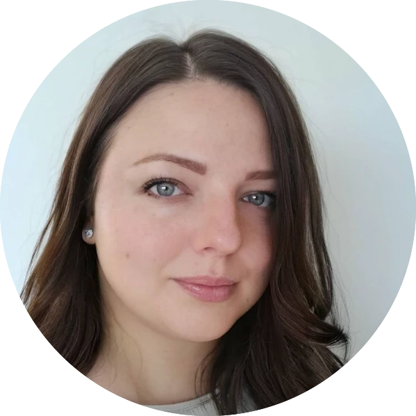 Portrait of a woman with wavy brown hair, light skin, and blue eyes against a plain light background.