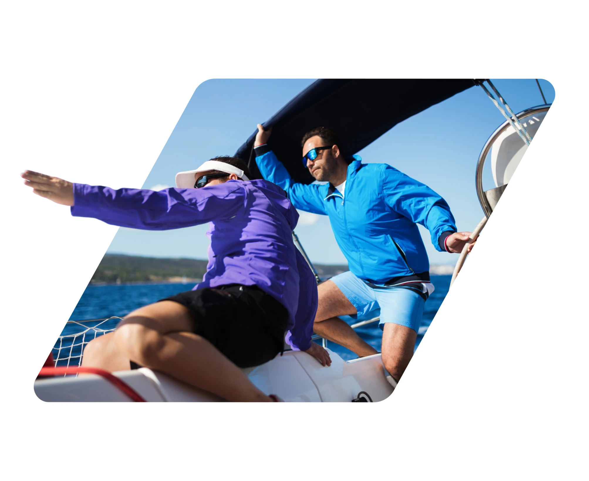 Two men in windbreakers and sunglasses handling sails on a sailboat on a sunny day.