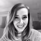 Black and white portrait of a smiling woman with straight hair wearing a striped shirt.