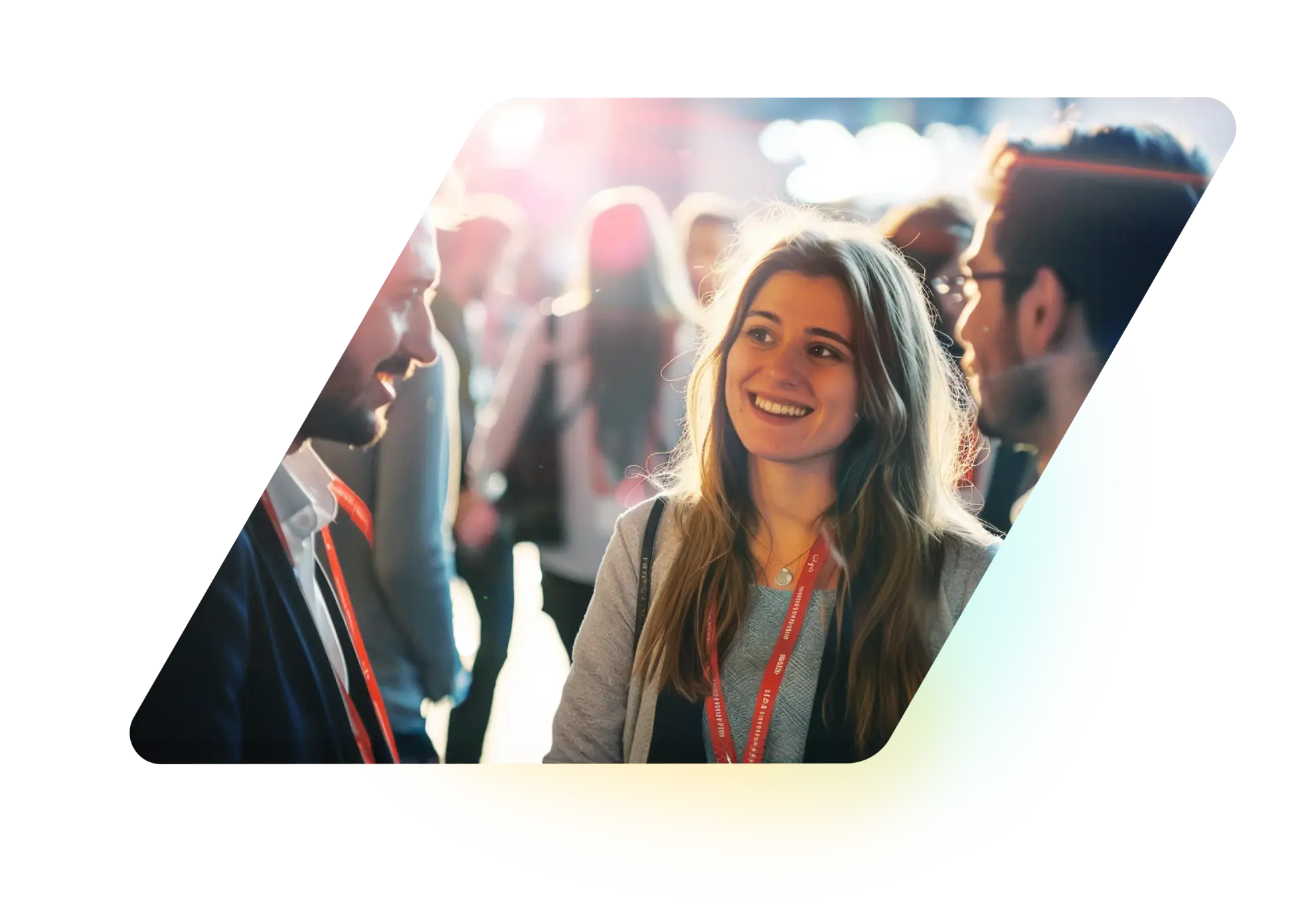 Smiling young woman wearing a red event lanyard talking to two men in a busy, well-lit conference or networking event.
