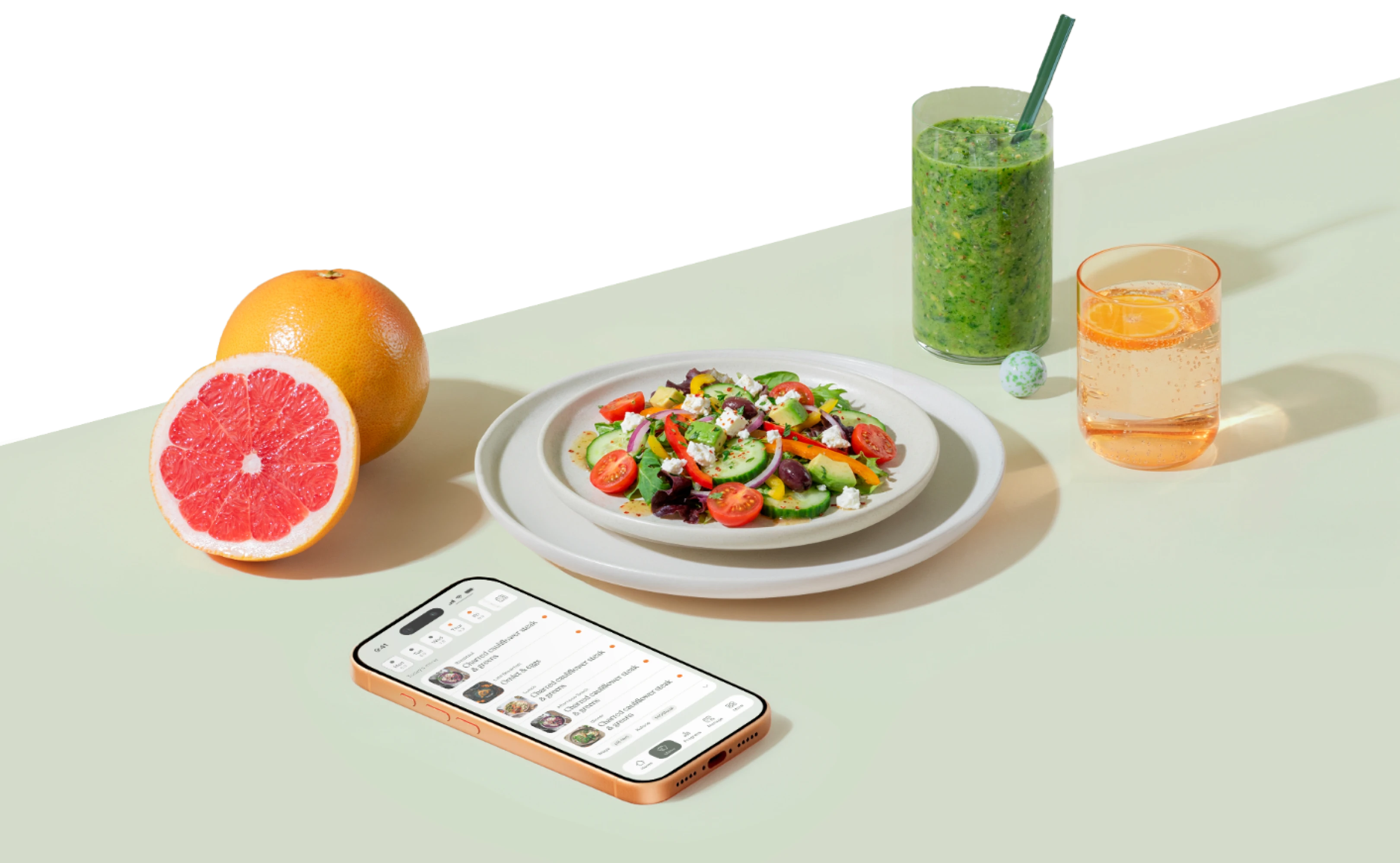 Table with a tasty meal next to smartphone with an app, around them is green smoothie, glass of water and half of grapefruit