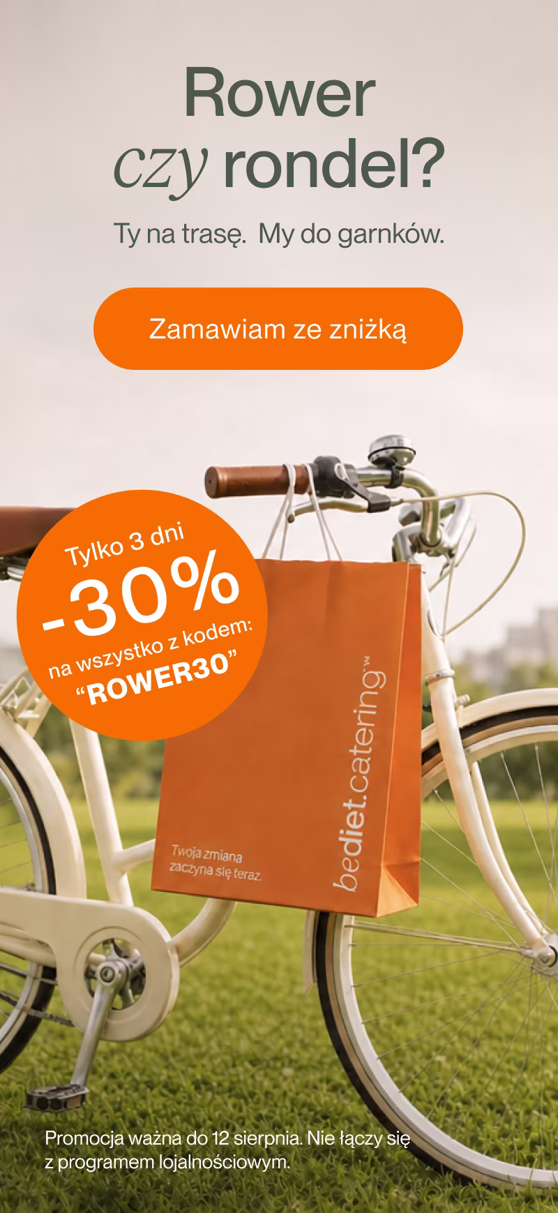 Trzy uśmiechnięte dorosłe osoby w kuchni, środkowa osoba w pomarańczowym fartuchu kucharskim, z przodu na blacie dwa soki i talerze z jedzeniem.