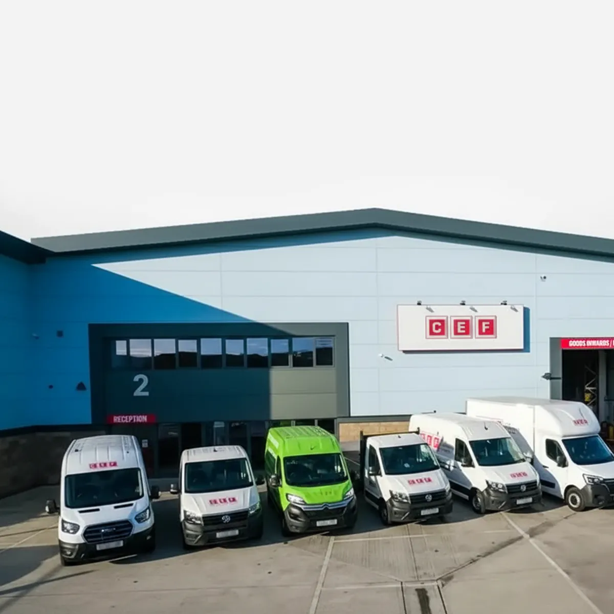 Fleet of six commercial vans parked outside a CEF warehouse marked with loading bay number 2 and a goods entrance.