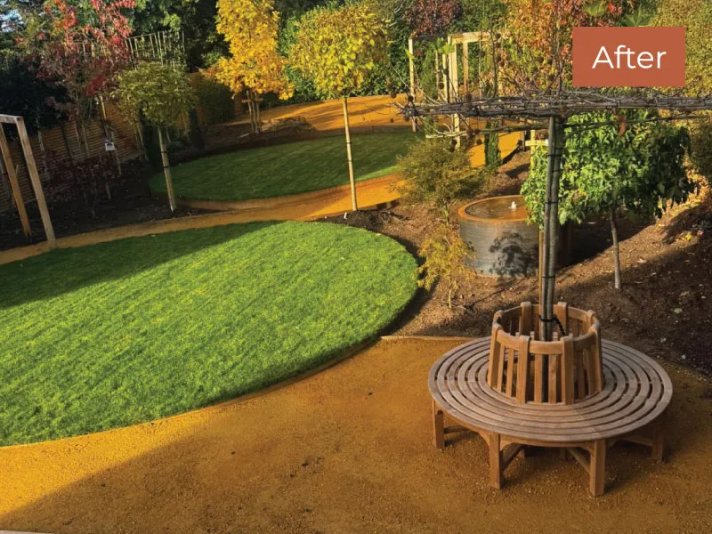 Well-maintained garden with circular green lawns, wooden tree bench, and a water feature under trees with autumn foliage.
