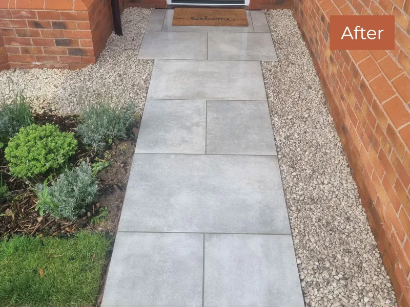 Newly installed grey stone pathway bordered by white gravel leading to a door with a welcome mat.