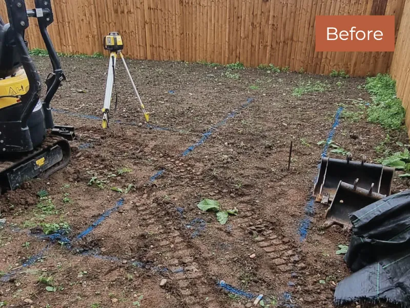 Backyard area with dirt ground marked by blue spray paint and construction equipment before patio installation.