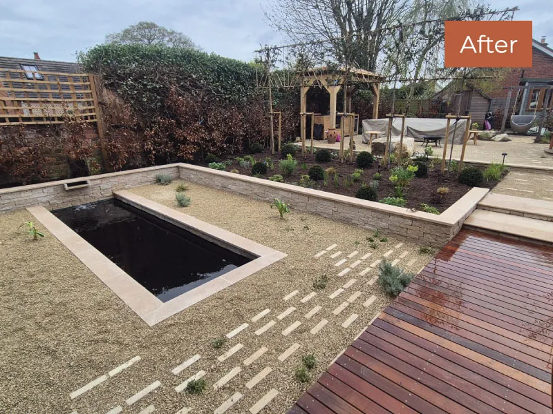 Modern backyard with rectangular water feature, gravel paths, raised garden bed, and wooden deck after landscaping.