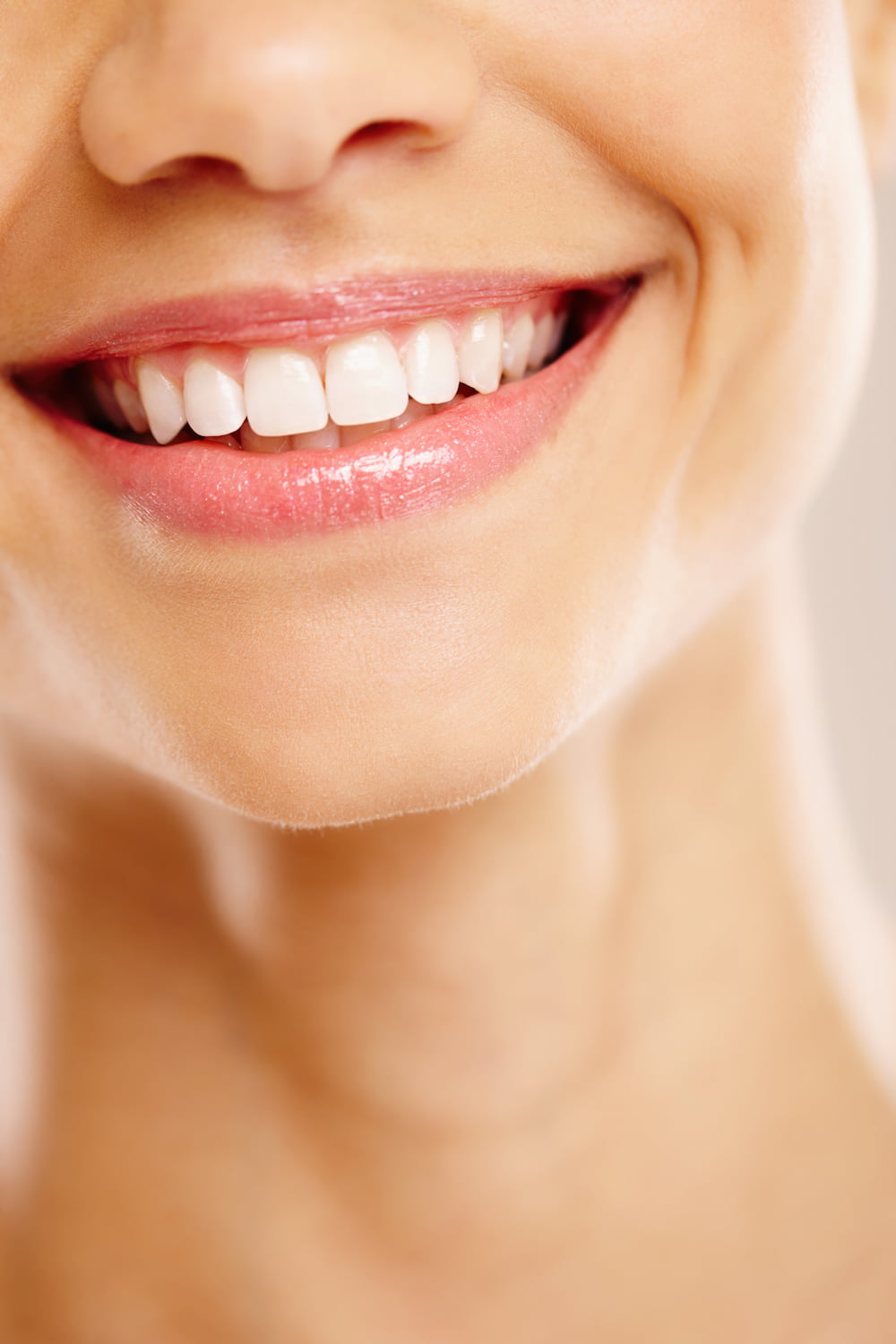 Close-up of a smiling mouth showing clean, white teeth and pink lips.