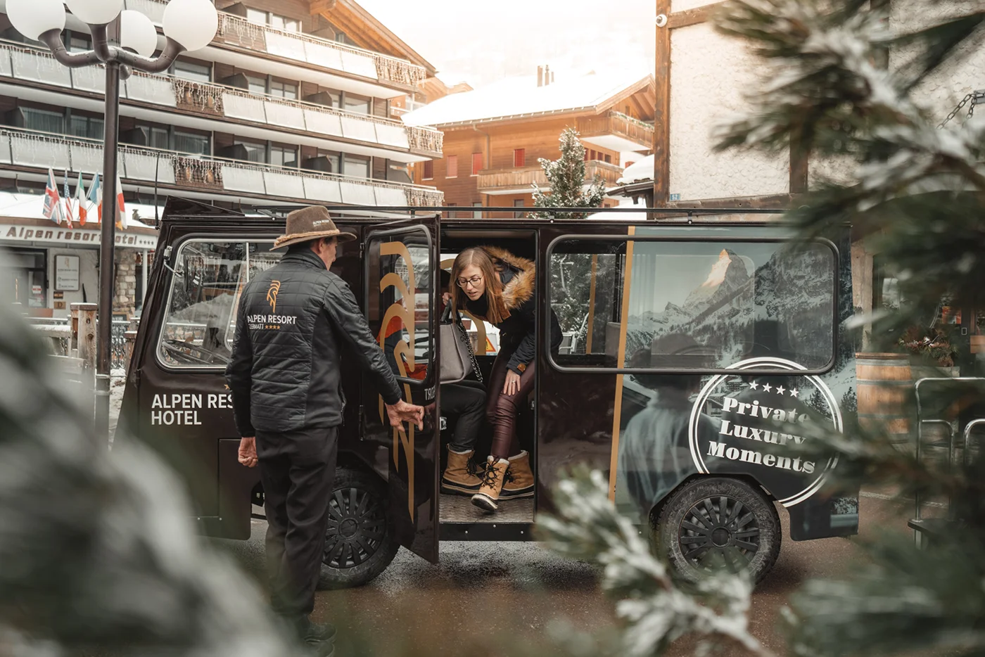 Mitarbeiter des Alpen Resorts öffnet die Türe des Elektromobils, damit die Gäste aussteigen können