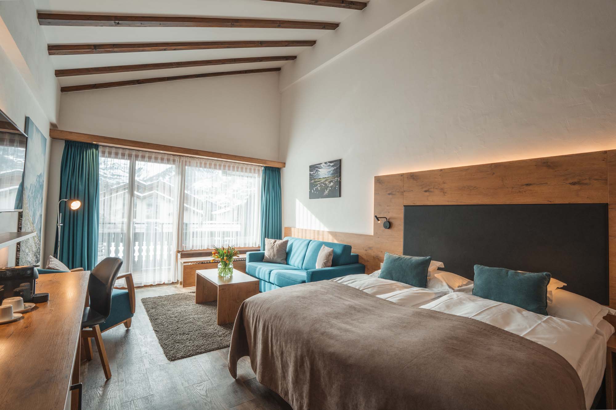 Helles Doppelzimmer im Alpen Resort & Spa Zermatt mit Balkon, Holzelementen und Blick auf die Alpen, komfortable Unterkunft für Ferien in Zermatt.