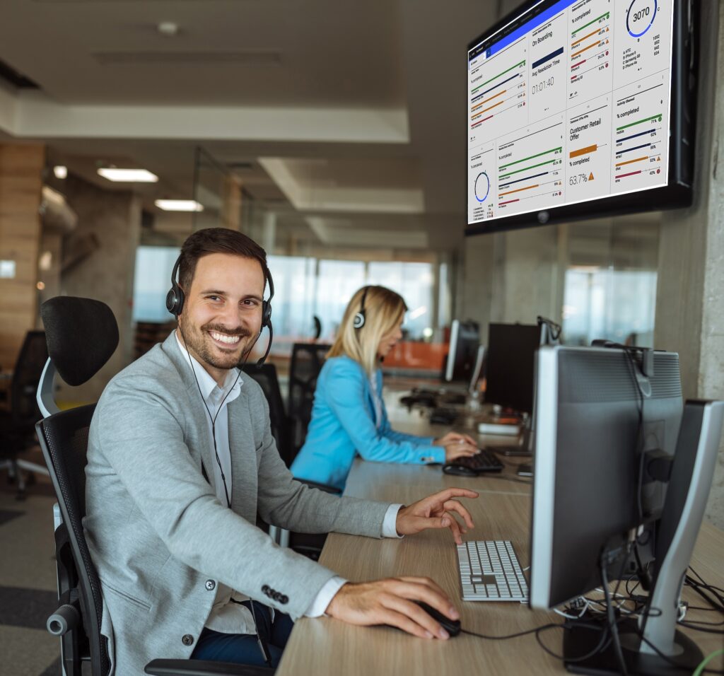 Call center employee smiling with a dashboard in the background
