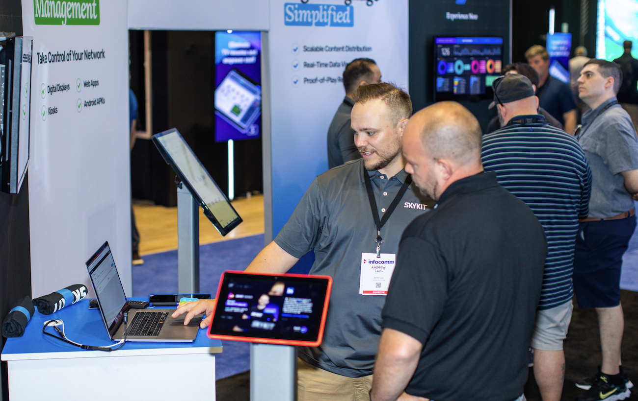 People interacting with digital displays at a trade show booth