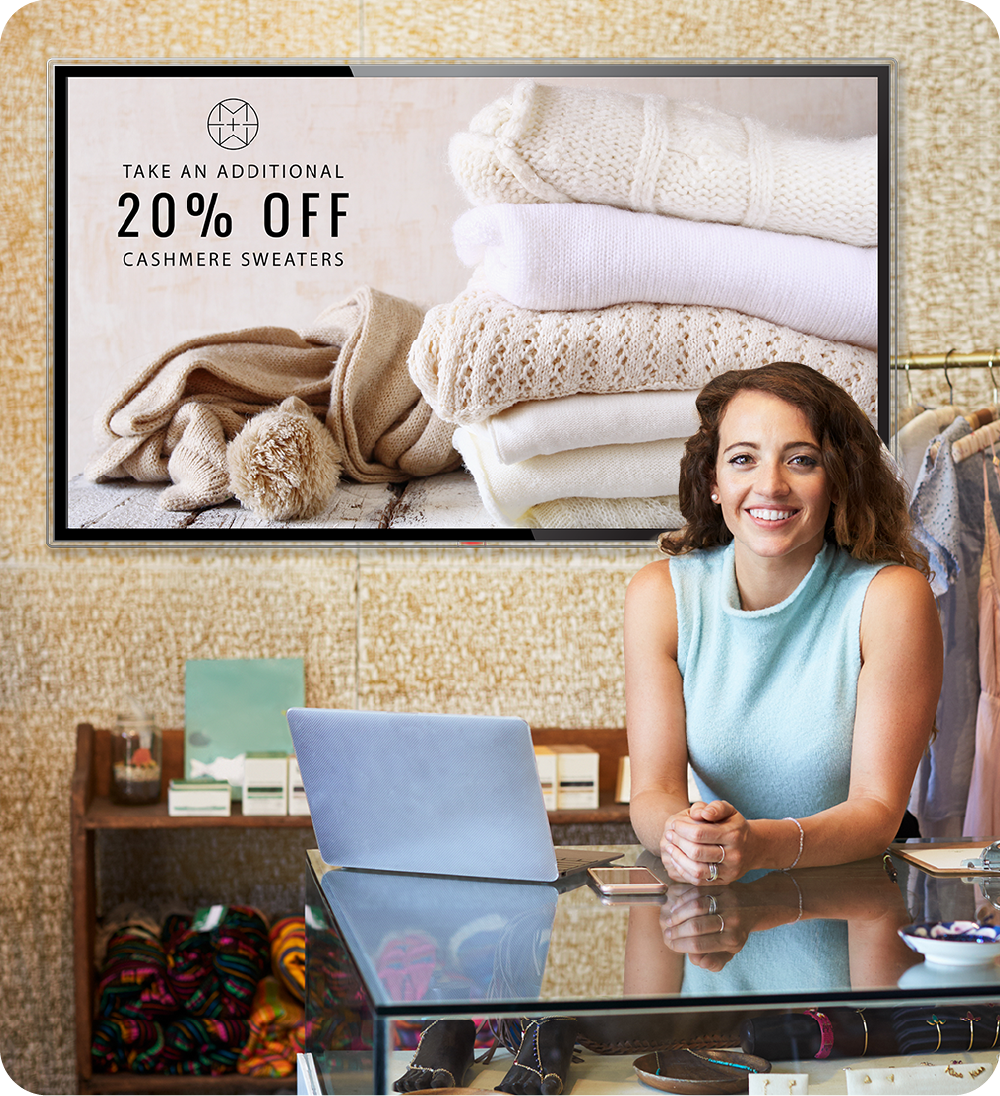 Retail store owner behind counter with digital signage displaying 20% off promotion