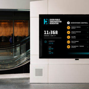 Large digital corporate directory display next to an indoor escalator