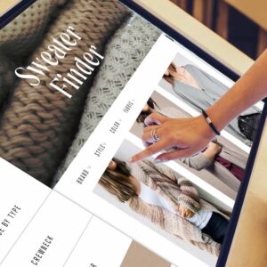 Close-up interaction with a tablet showing a sweater finder app
