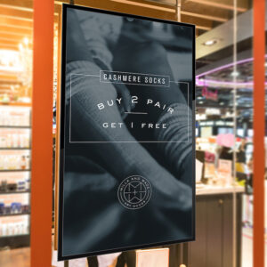 Digital signage display in a retail store promoting a buy 2 get 1 free sale on socks