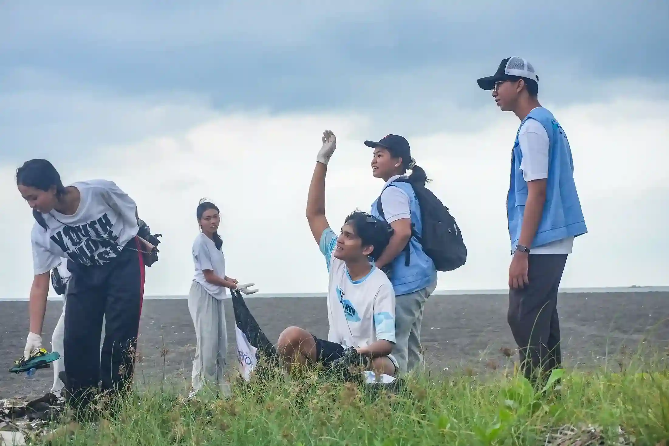 Young volunteers collecting trash during a beach clean-up at Biaung Beach, protecting ocean health