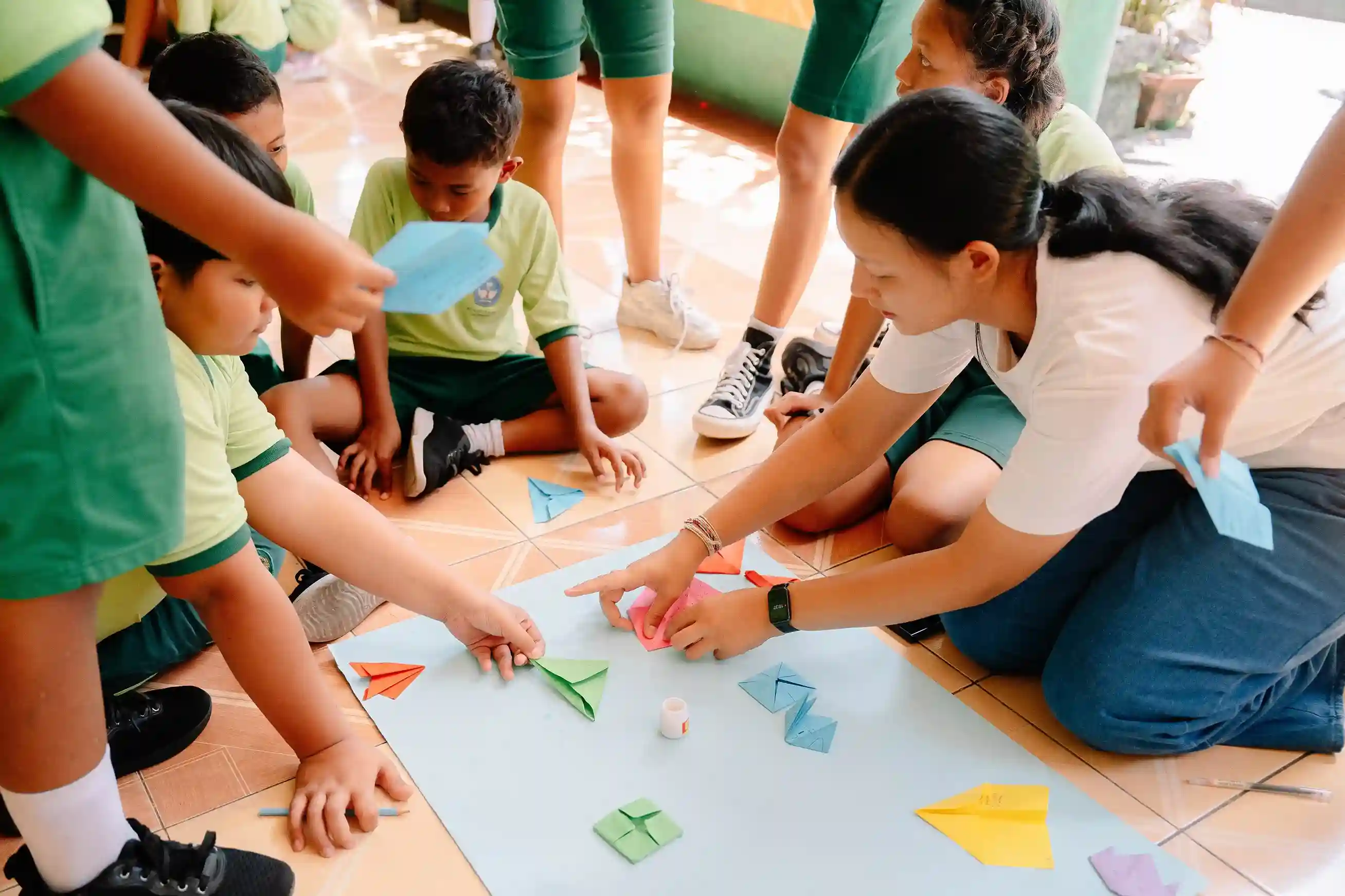 Children and teacher doing colorful paper folding activity for waste awareness education program